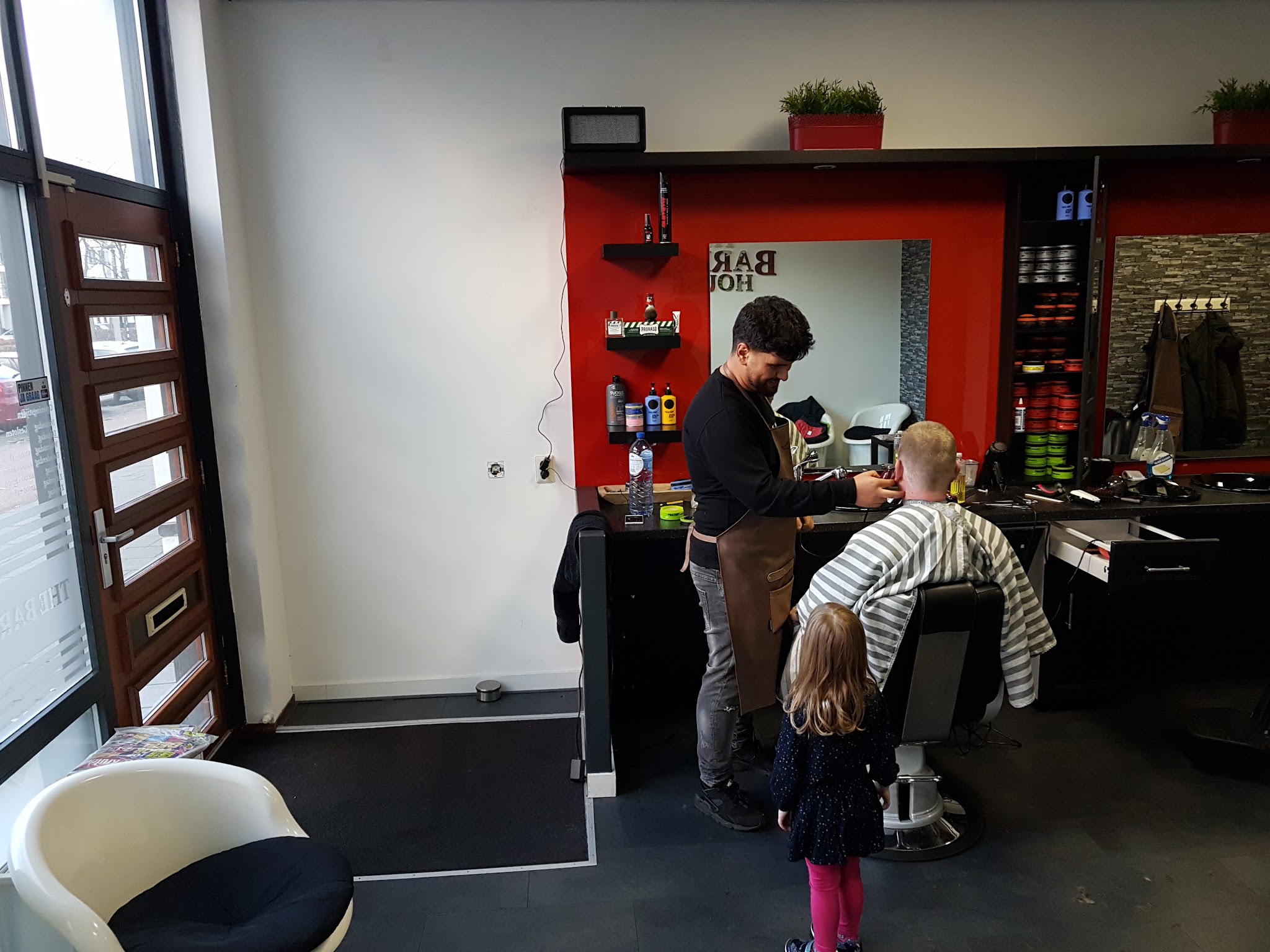 De barbier aan het werk bij de spiegel met rode lijst